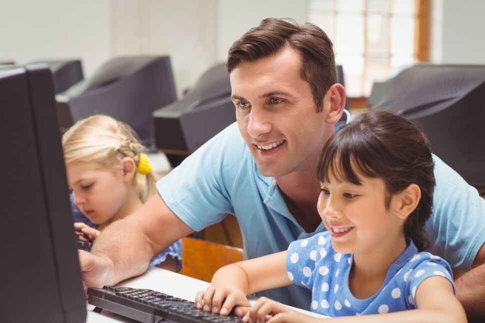 teacher-helping-children-behind-computer