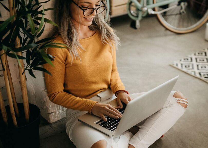 woman-sitting-on-ground-working-on-laptop