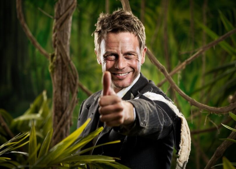 man-with-torn-up-suit-in-jungle-raising-thumb