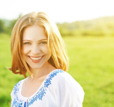woman-standing-in-field-and-smiling