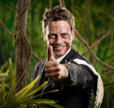 man-with-torn-up-suit-in-jungle-raising-thumb